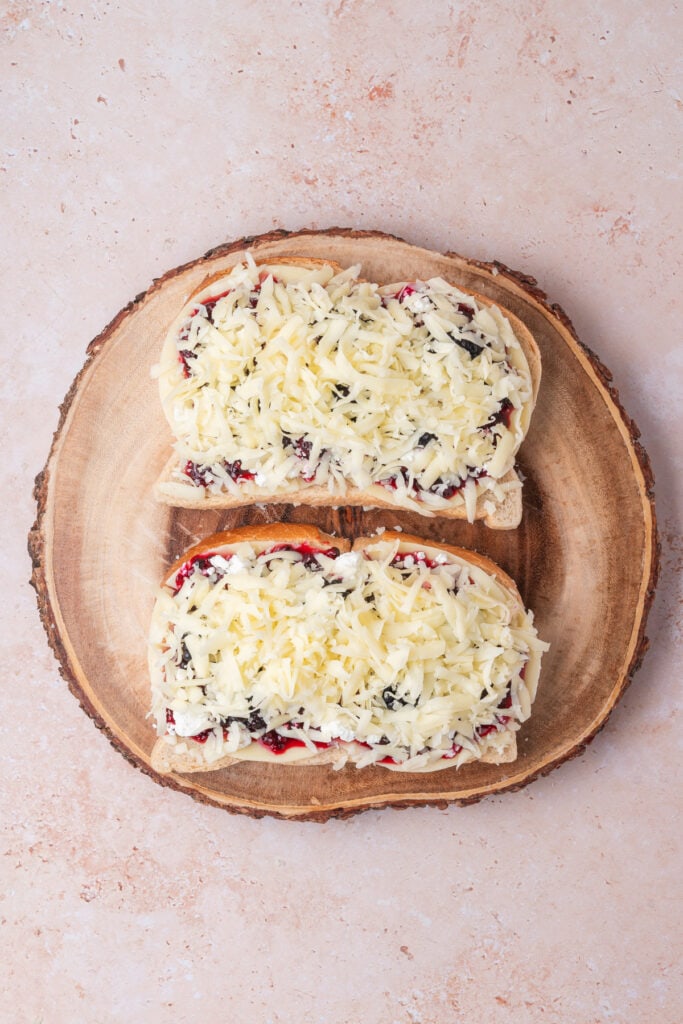 Final cheese layer of shredded mozzarella added on top of the jam and goat cheese