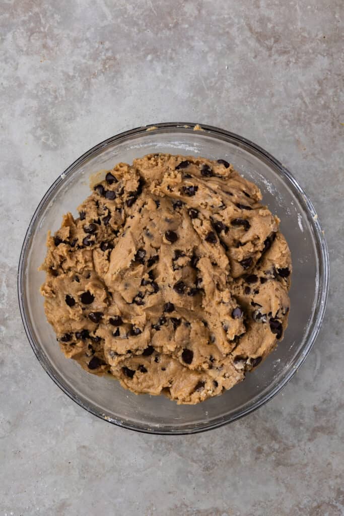 Fully mixed cookie dough with chocolate chips evenly distributed in a glass bowl.