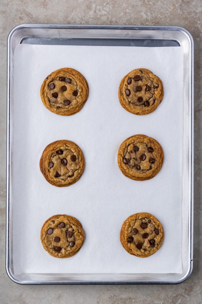 Freshly baked brown butter sourdough chocolate chip cookies on a baking sheet, still warm.