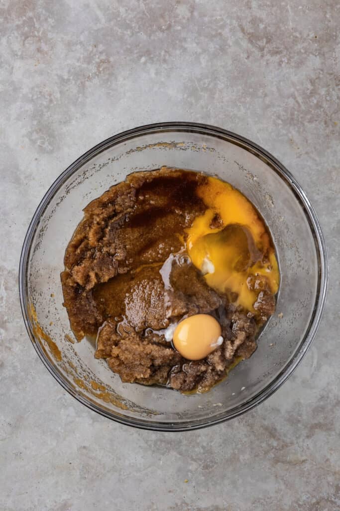 Eggs and vanilla added to the brown sugar and butter mixture in a mixing bowl.