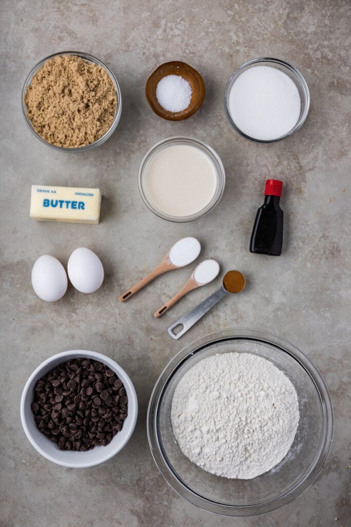 Overhead view of measured ingredients for brown butter sourdough discard chocolate chip cookies, including flour, sugar, eggs, vanilla, butter, sourdough discard, and chocolate chips.