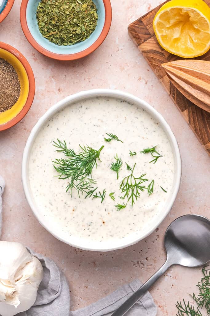 Lemon dill dressing in a white bowl topped with fresh dill sprigs.