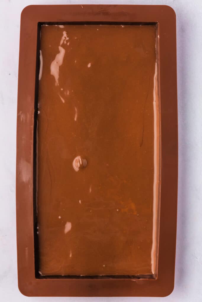 Final chocolate layer spread smoothly in a silicone mold, sealing the Dubai Chocolate Bar.
