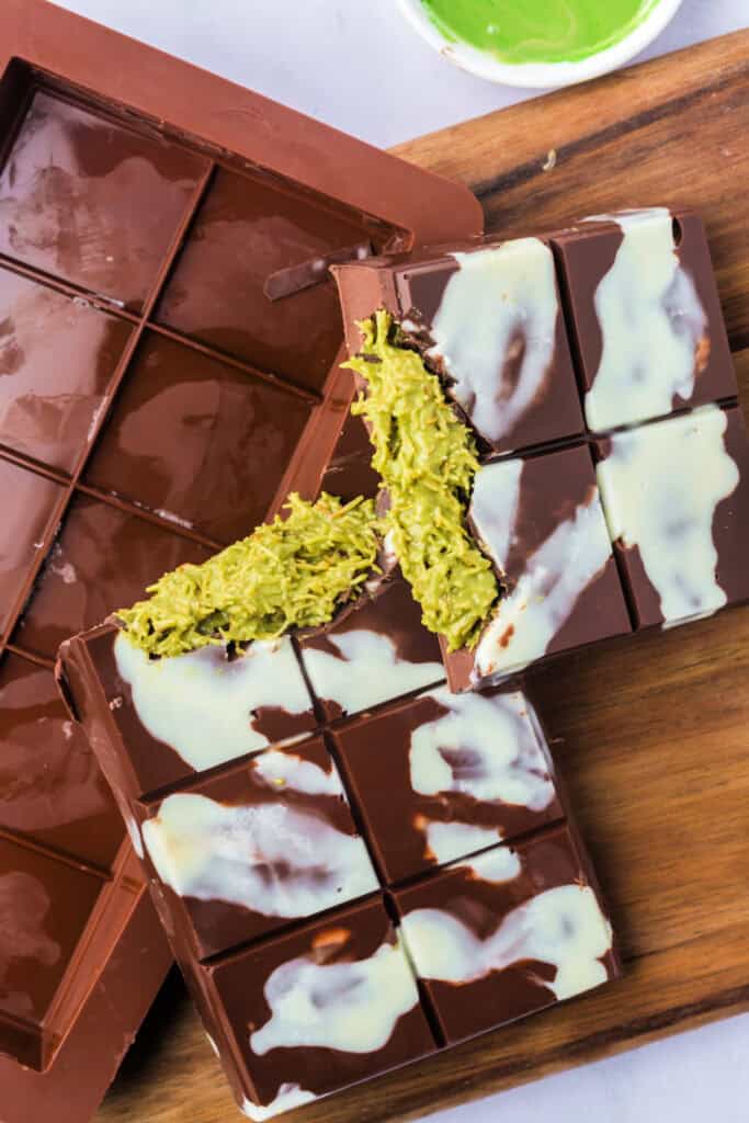 Top-down view of a sliced Dubai Chocolate Bar on a wooden board, highlighting the creamy green pistachio filling.