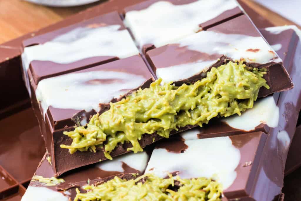 Macro shot of a cross-section of the Dubai Chocolate Bar showing gooey pistachio filling with kataifi strands and chocolate layers.