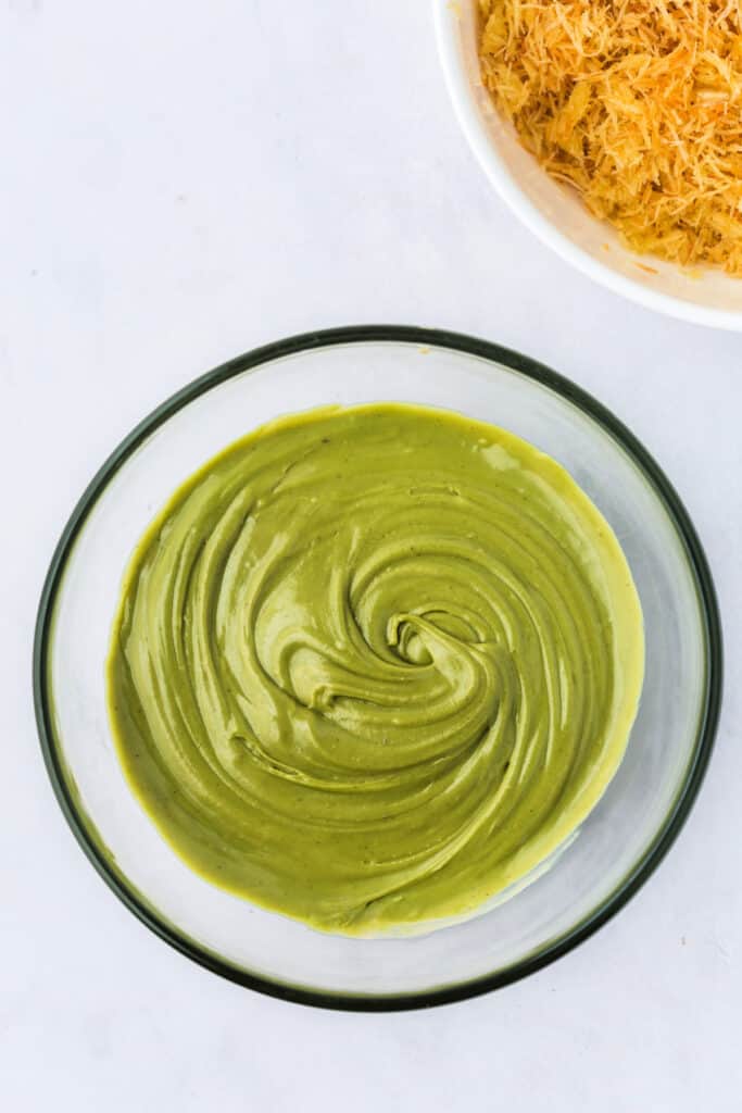 Smoothly mixed pistachio butter and tahini in a glass bowl, forming a creamy green base.