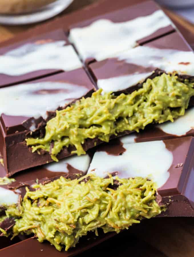 Square crop of two Dubai Chocolate Bars stacked on top of each other with visible green pistachio filling and white chocolate drizzle.