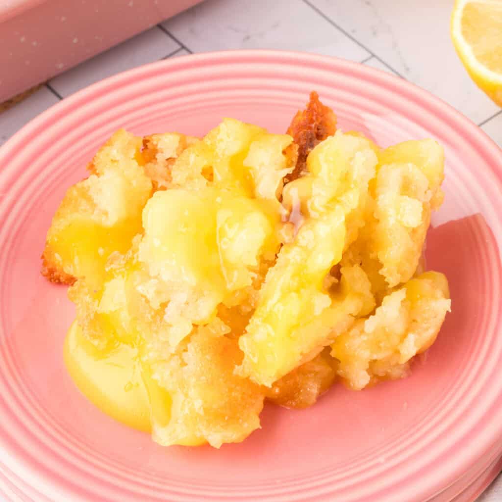 closeup of a scoop of This Easy Lemon Cobbler is the ultimate lemon dessert! Made with pie filling and a simple batter, it's buttery, tangy, and perfect with ice cream. on a pink plate