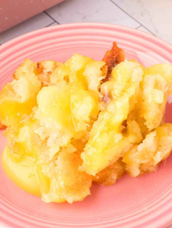 closeup of a scoop of This Easy Lemon Cobbler is the ultimate lemon dessert! Made with pie filling and a simple batter, it's buttery, tangy, and perfect with ice cream. on a pink plate