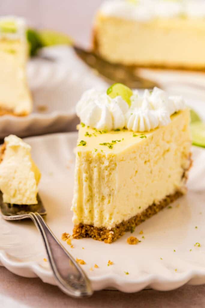 Slice of Key Lime Cheesecake on a plate with a bite taken from the tip