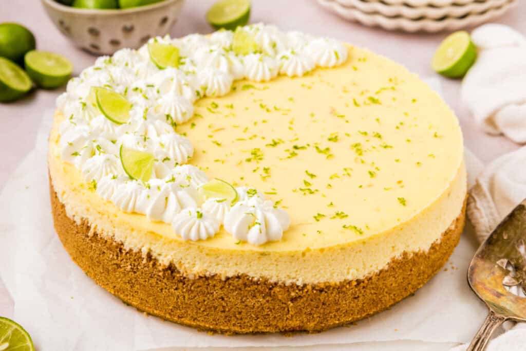 Side angle of Key Lime Cheesecake with lime zest and piped whipped cream