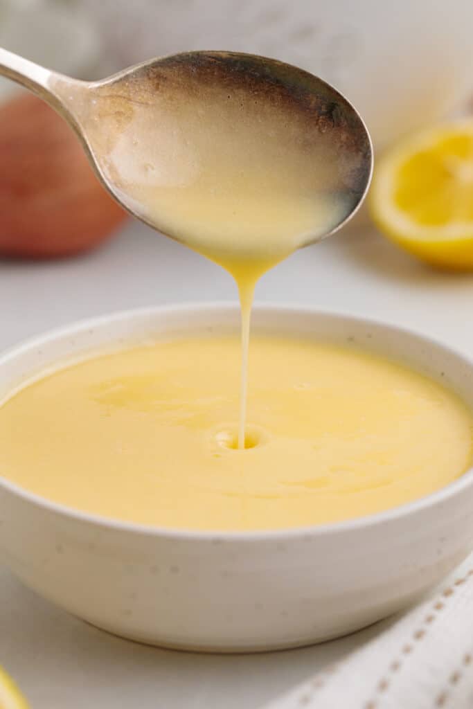 closeup of lemon butter sauce being poured off spoon into bowl