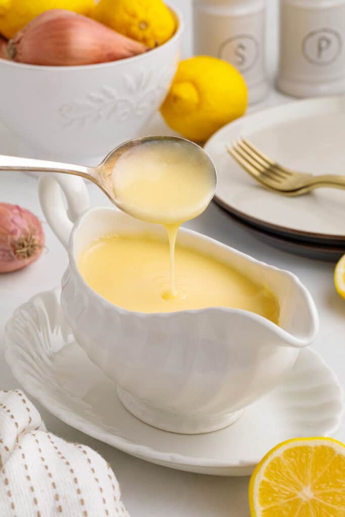 spoon pouring lemon butter sauce into gravy boat