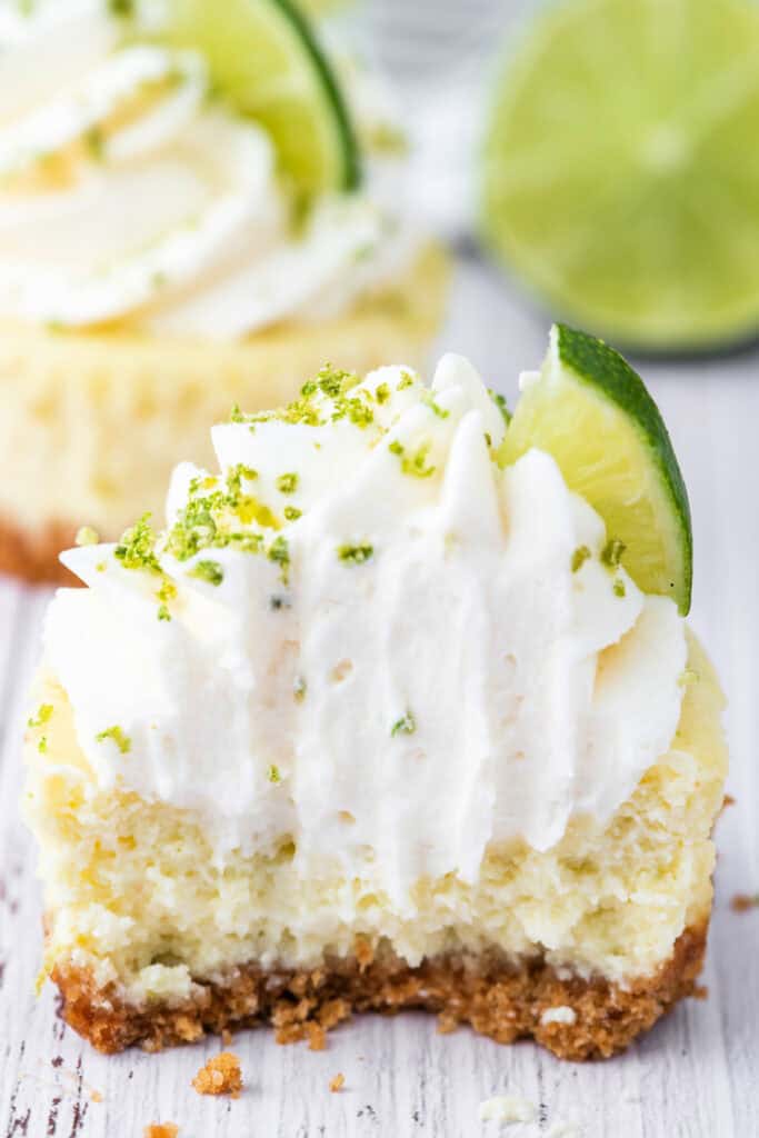 Close-up of a mini key lime cheesecake with a bite taken out, showing creamy texture