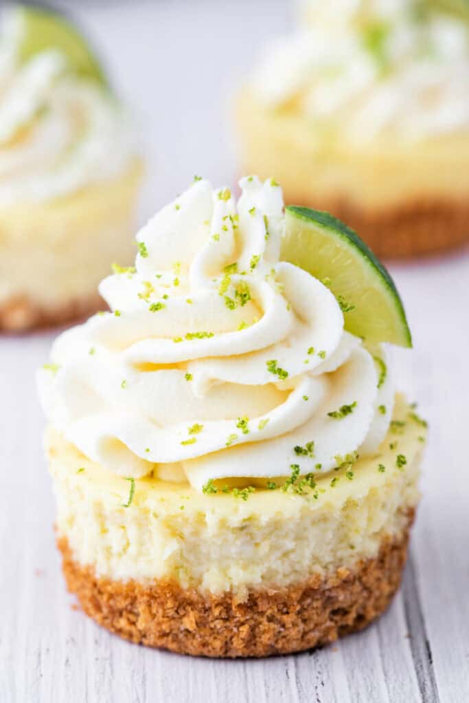 Close-up of a mini key lime cheesecake topped with whipped cream and sprinkled with lime zest