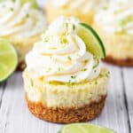 Mini key lime cheesecake with whipped cream swirl, lime zest, and lime slice garnish