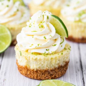 Mini key lime cheesecake with whipped cream swirl, lime zest, and lime slice garnish