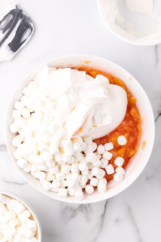 Whipped topping and mini marshmallows added to the peach fluff mixture.