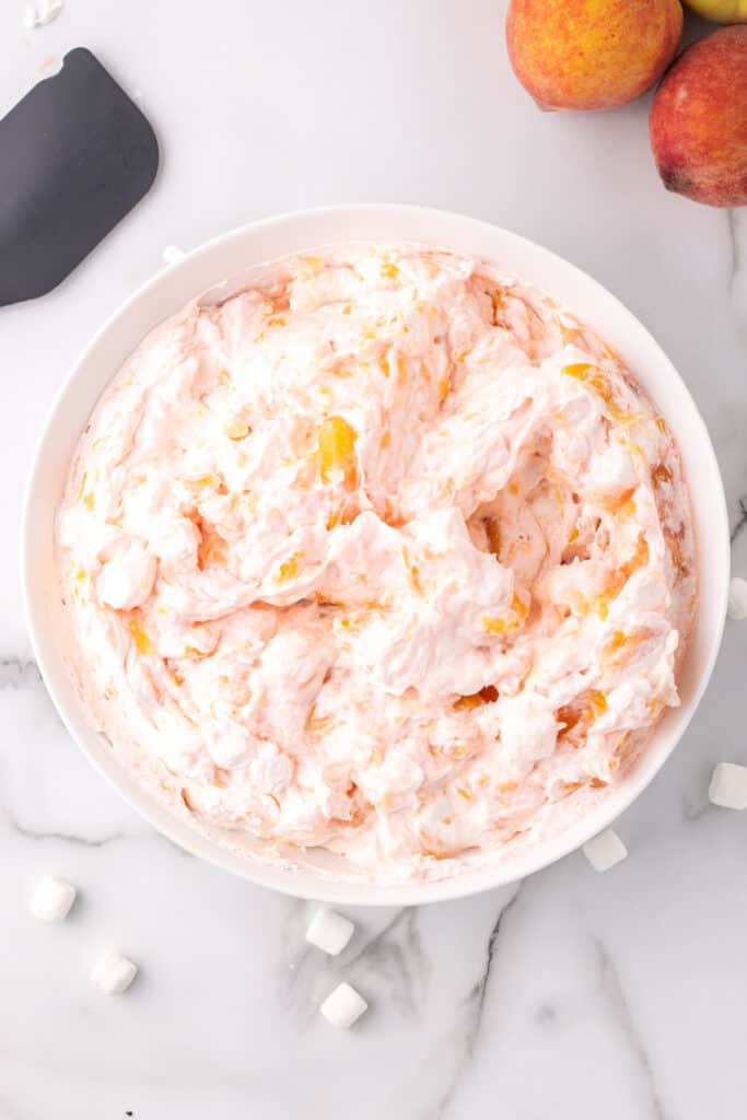 Fully combined peach fluff salad in a white mixing bowl.