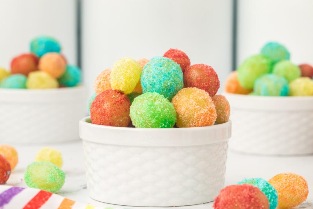 Front view of a white ramekin packed with brightly colored Sour Patch Grapes with other bowls in the background
