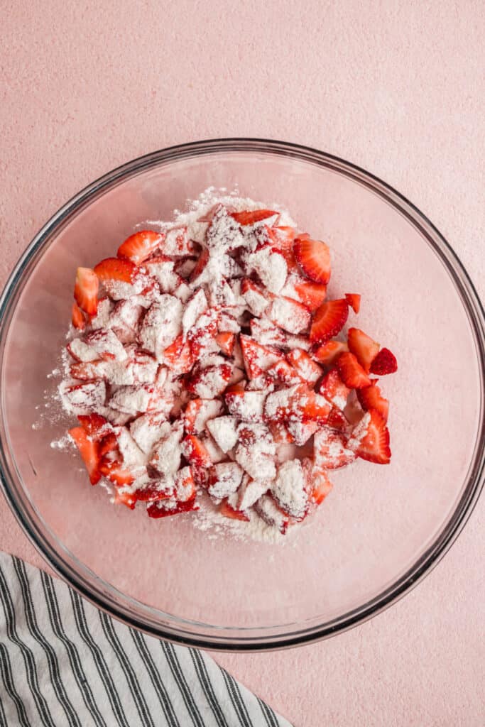Sliced strawberries tossed with flour in a glass mixing bowl
