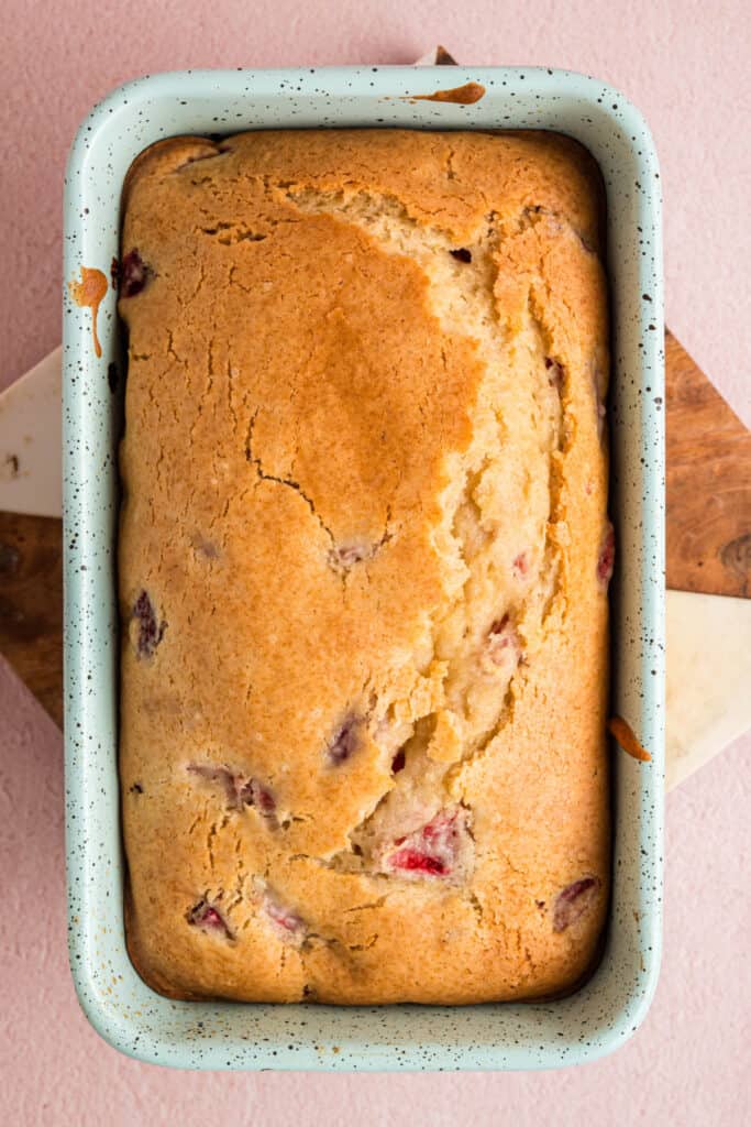 Baked strawberry bread loaf with golden brown top still in the loaf pan