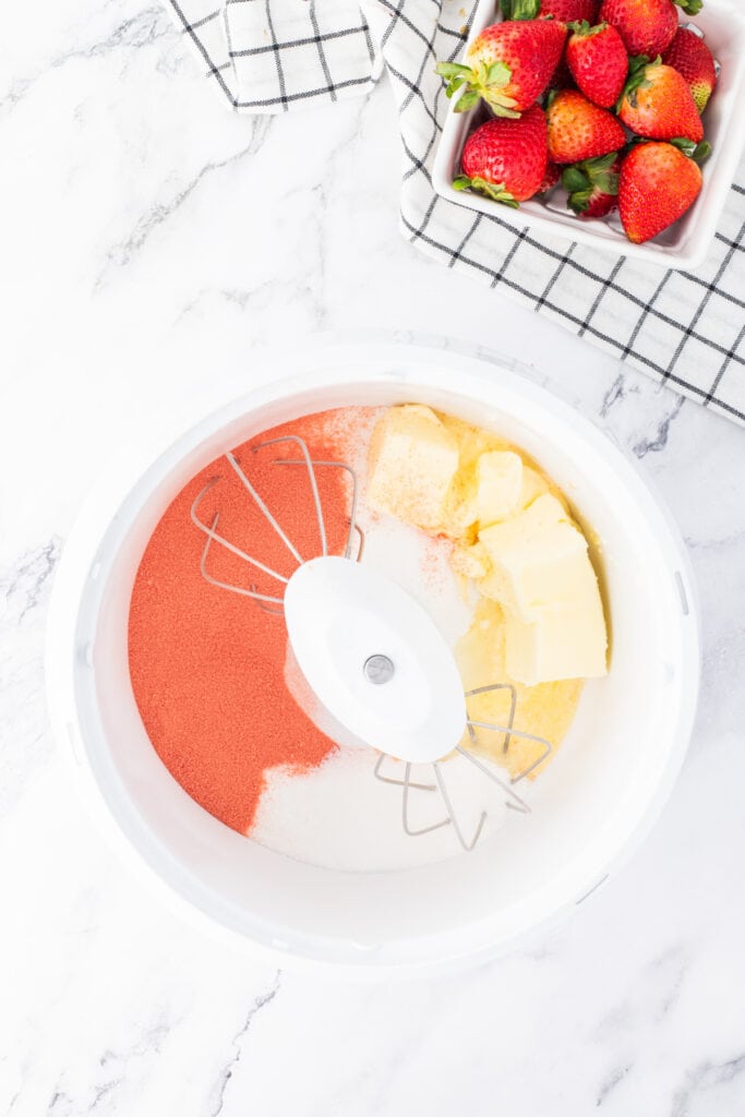 Butter, sugar, and strawberry Jello in a mixing bowl ready to be creamed together.