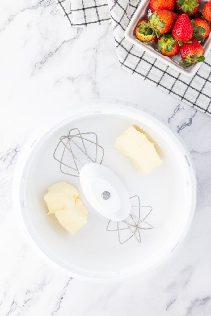 Room temperature butter added to a mixing bowl in preparation for strawberry frosting.