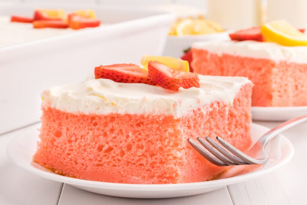 slice of strawberry cake with lemon cream topping on plate
