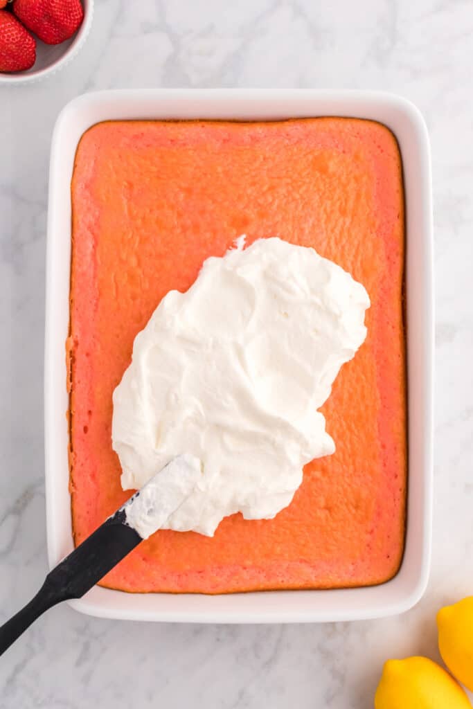 spreading the lemon cream topping over the top of the strawberry cake