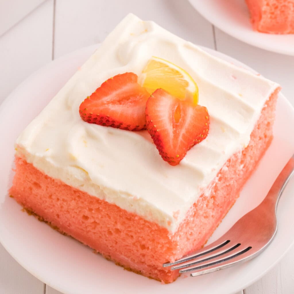 closeup of a slice of strawberry cake with lemon cream topping on plate