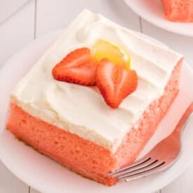 closeup of a slice of strawberry cake with lemon cream topping on plate