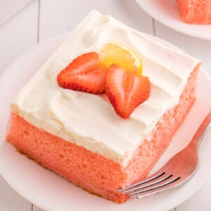 closeup of a slice of strawberry cake with lemon cream topping on plate