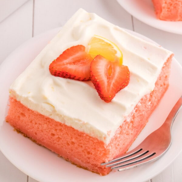 closeup of a slice of strawberry cake with lemon cream topping on plate