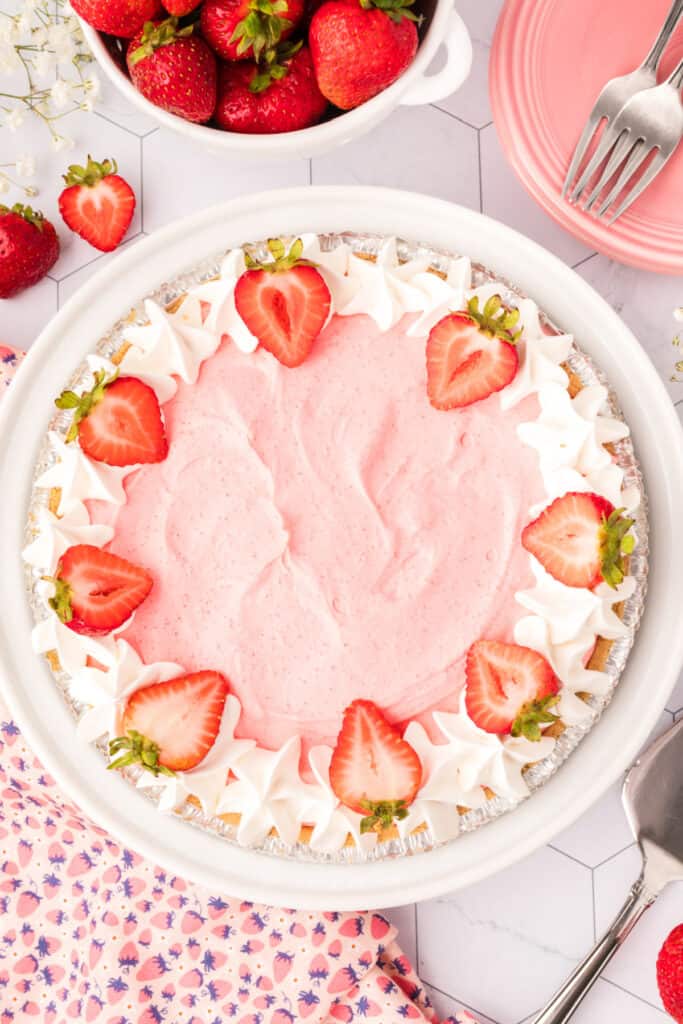 Decorated strawberry cream pie with piped whipped topping and halved strawberries on top, ready to serve