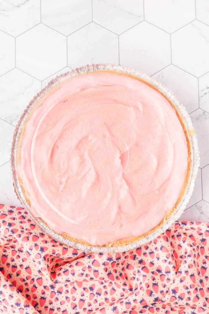 Overhead view of the finished strawberry cream pie before chilling, swirled pink surface