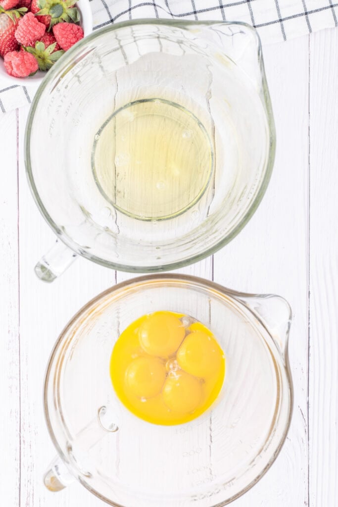 Smooth and airy egg yolk mixture in a glass bowl with a red spatula, prepared for tres leches cake batter.