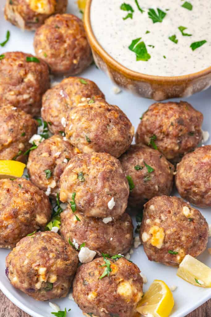 Closeup of plated turkey feta meatballs with lemon wedges and dipping sauce