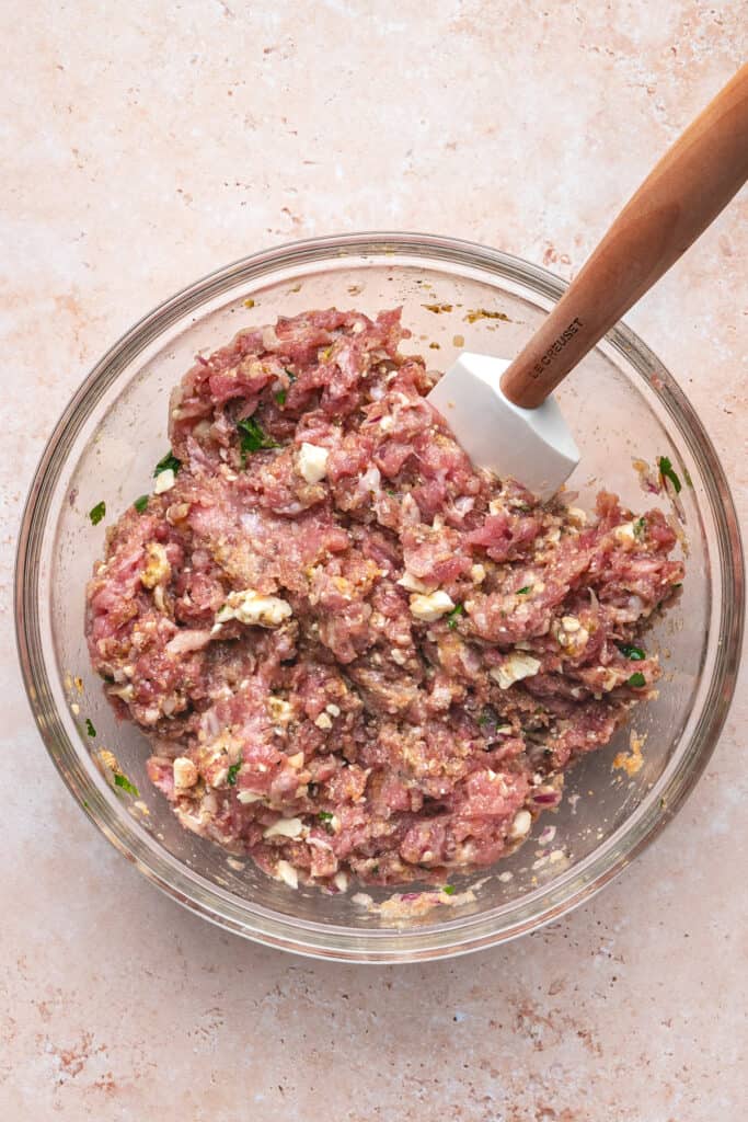 Mixed turkey meatball mixture in a glass bowl with spatula ready for scooping