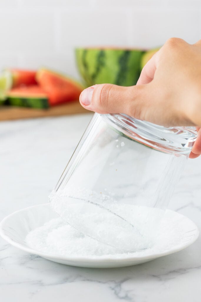 Hand dipping a glass into coarse salt to rim it for margaritas