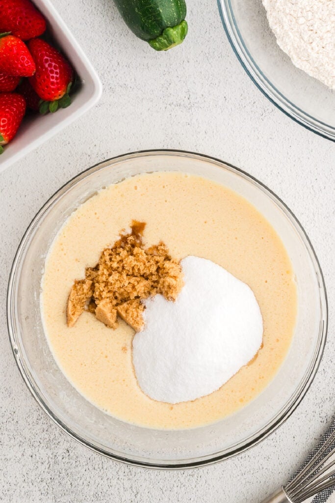 Granulated sugar and brown sugar added to the bowl of whisked wet ingredients