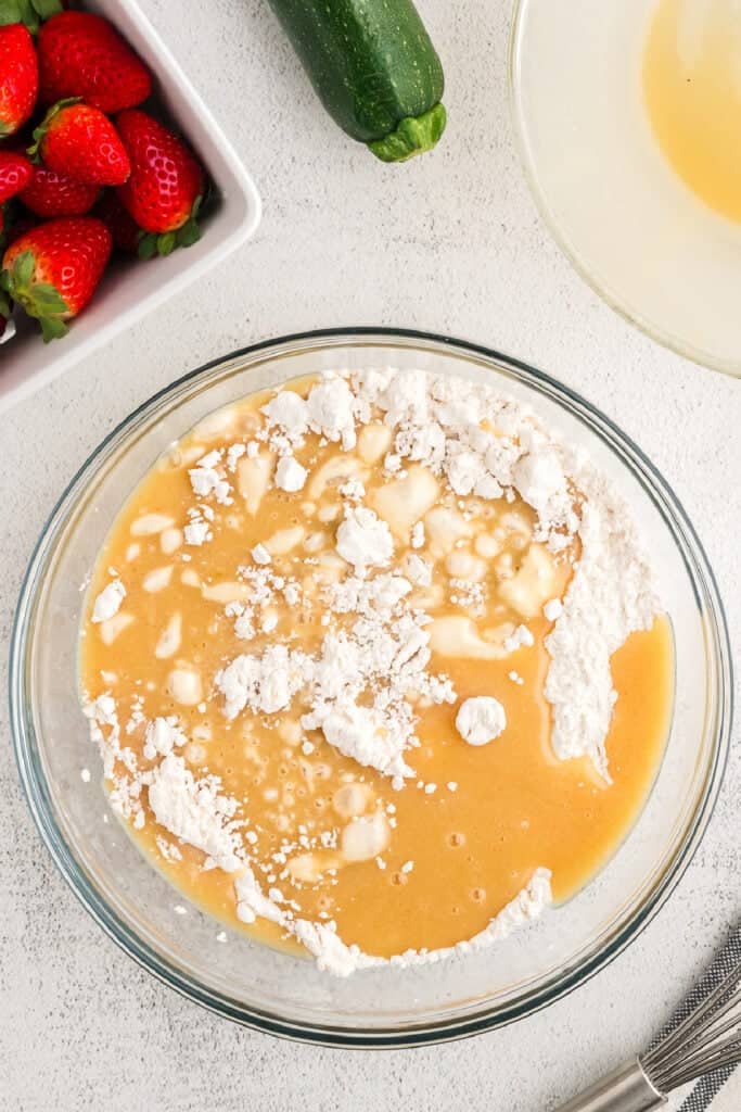 Wet and dry ingredients just combined in a glass bowl with visible flour clumps