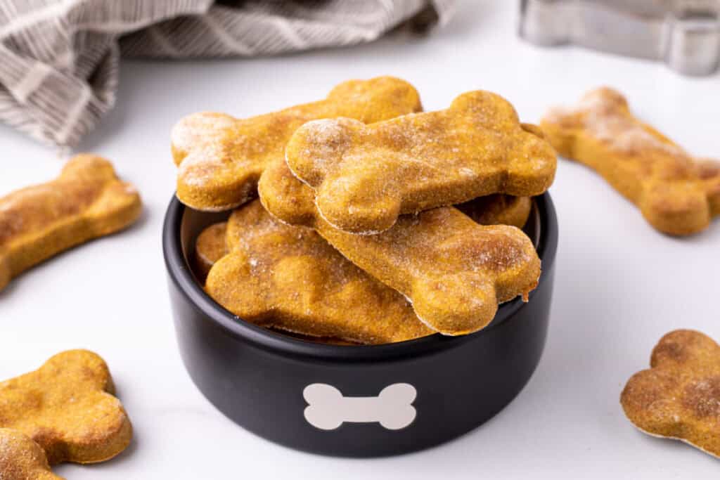 Finished air fryer dog treats stacked in a black dog bowl with a bone symbol on it.