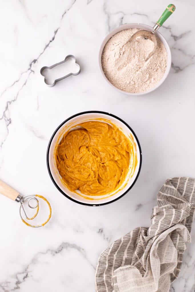 Mixed pumpkin, peanut butter, and egg batter in a white bowl ready for flour addition.
