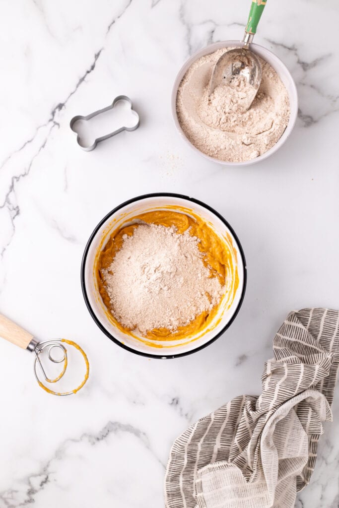 Whole wheat flour added to pumpkin mixture to make homemade dog treat dough.