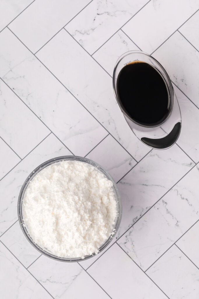 Powdered sugar and Kahlua measured for the glaze on a marble surface.