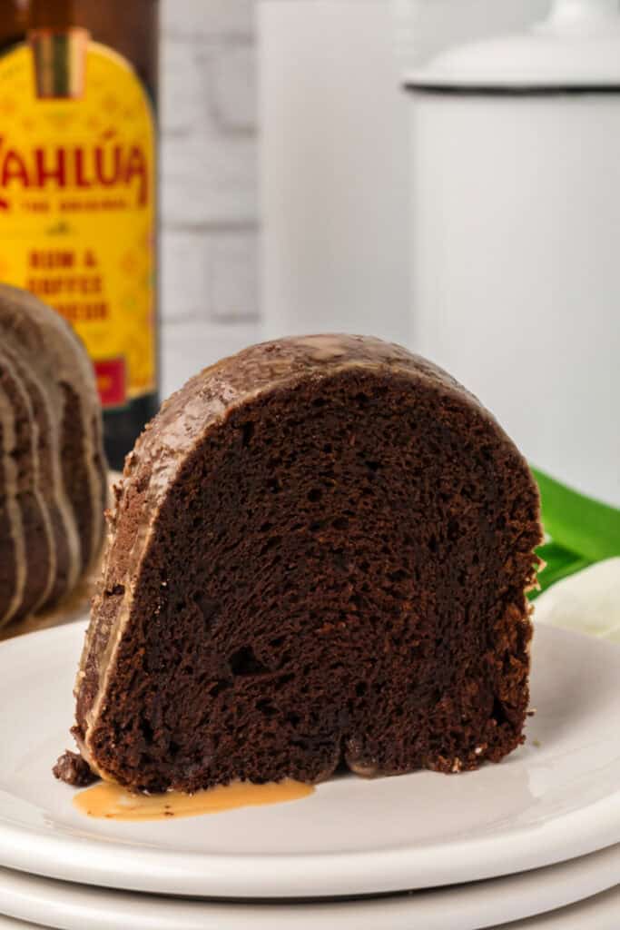 Slice of Chocolate Kahlua Bundt Cake on a white plate with Kahlua bottle in the background.