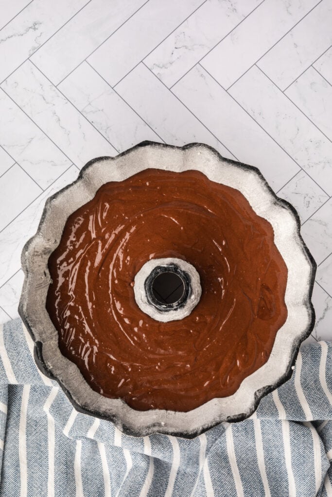 Chocolate cake batter poured evenly into a prepared Bundt pan.