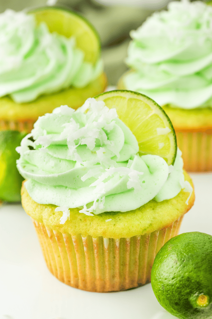 Decorated coconut lime cupcake topped with frosting, coconut, and lime slice