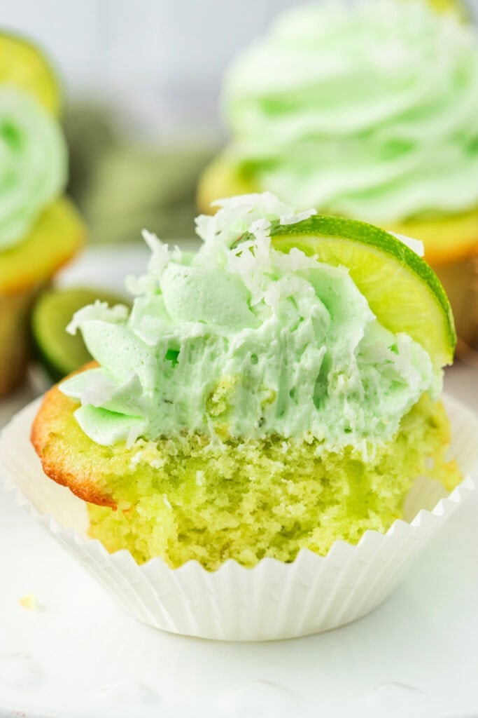 Close-up of a coconut lime cupcake with a bite taken out to show texture